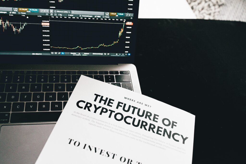 Cryptocurrency trading charts displayed on a laptop screen next to a paper report analyzing the future of decentralized finance and crypto markets.